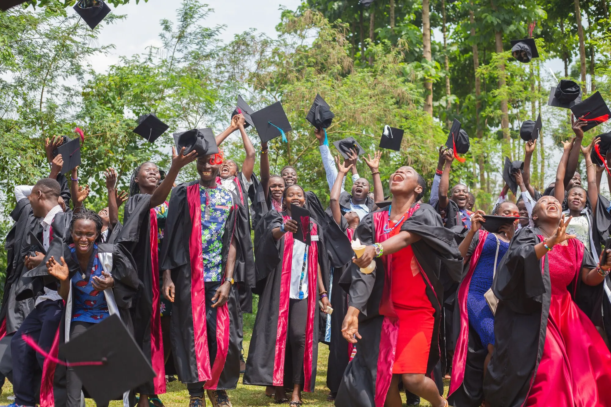 Kira Farm graduates in gowns throwing their caps in the air