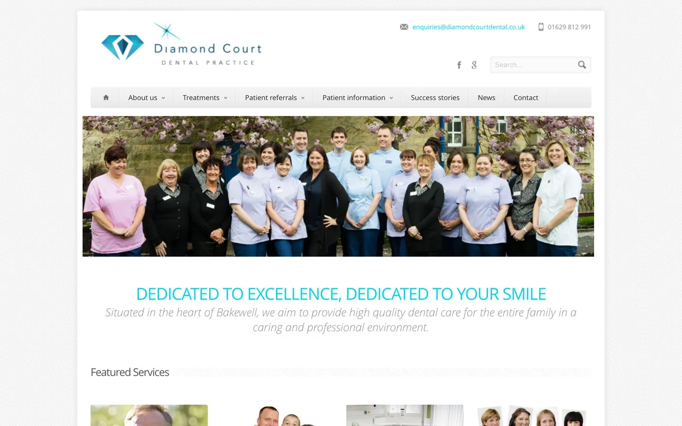 The 2013 site soon after launch: the refreshed diamond logo, a grey menu bar and a photo of the team outdoors, above “Dedicated to excellence, dedicated to your smile”