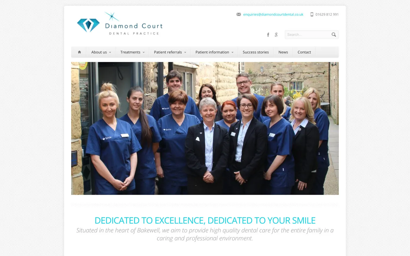 The 2013 home page: a boxed layout under the diamond logo, a grey menu bar, a slideshow photo of the team and “Dedicated to excellence, dedicated to your smile”