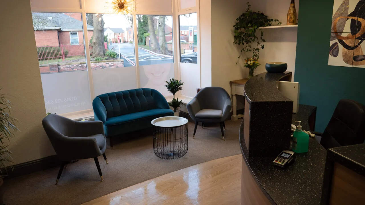 The bay-window waiting area at Ferndale House: a teal sofa and two armchairs by the window onto the street