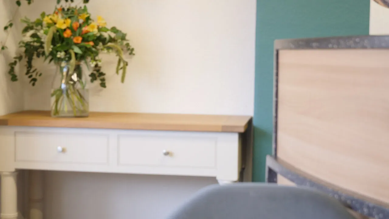 The interview set upstairs: a bunch of flowers on a white sideboard, the practice’s teal wall and the back of the interview chair