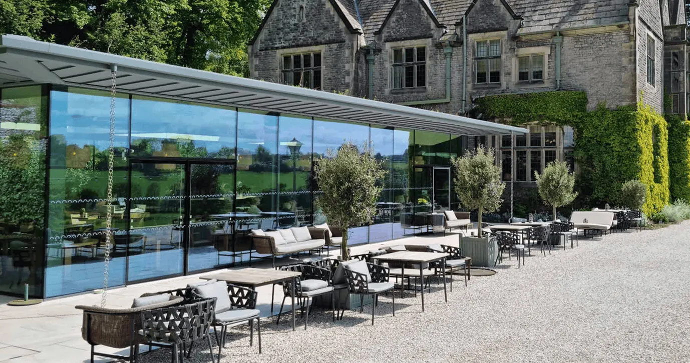 A glass pavilion beside a stone hall: one of Planning & Design Practice’s projects, from their website