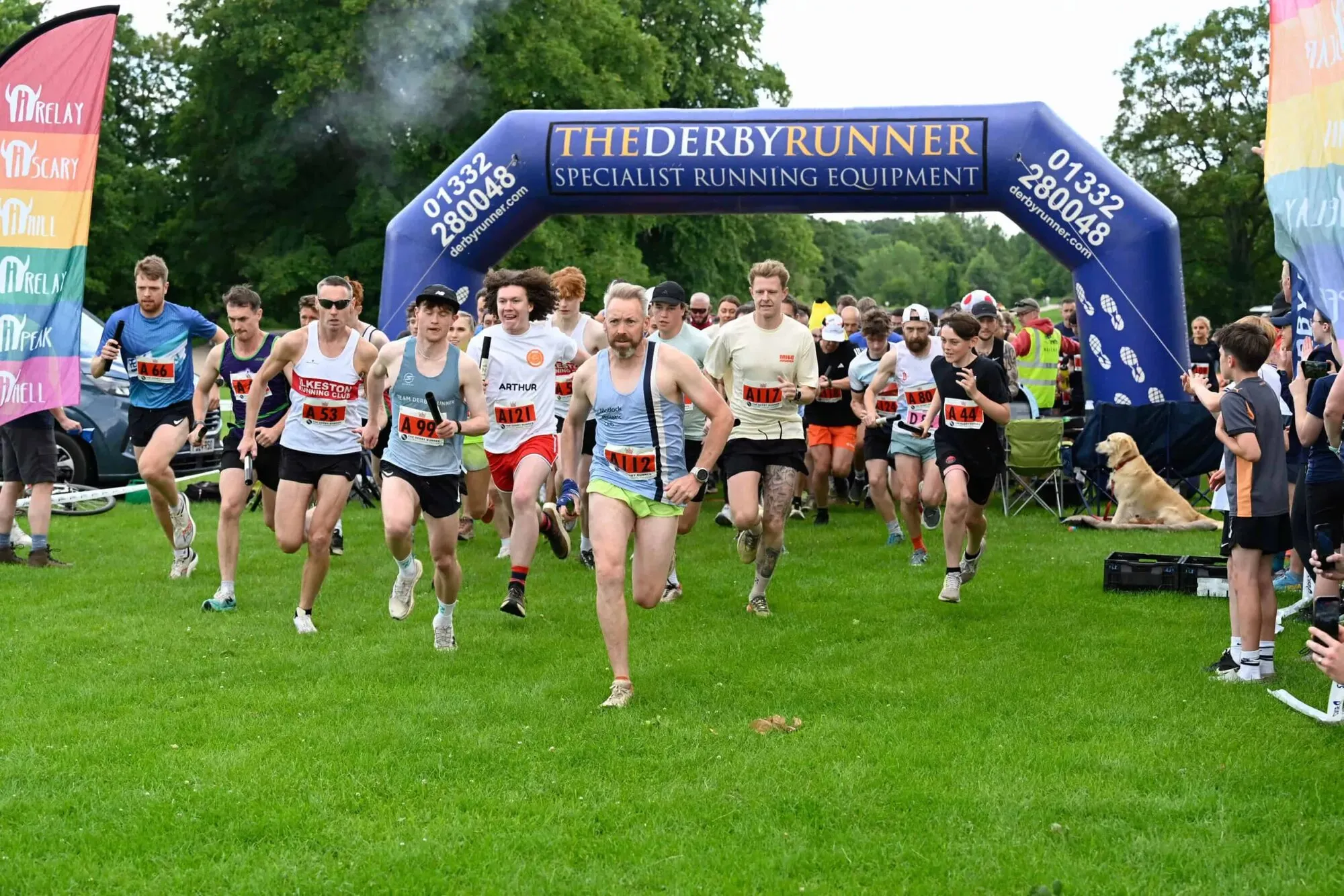 The start of a race in a park: runners setting off under an inflatable arch