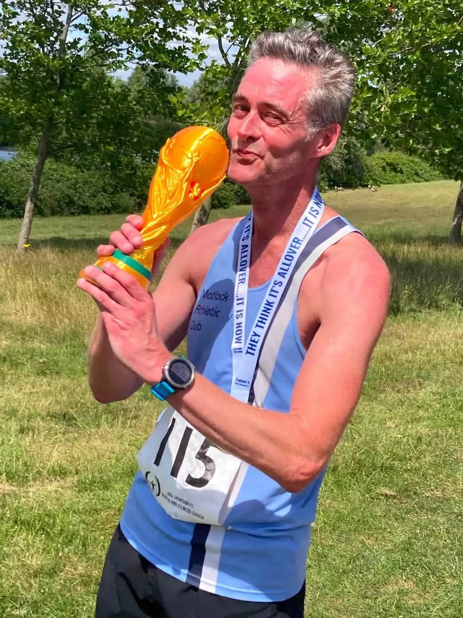 A Matlock runner wearing number 115 kissing a gold replica of the football World Cup