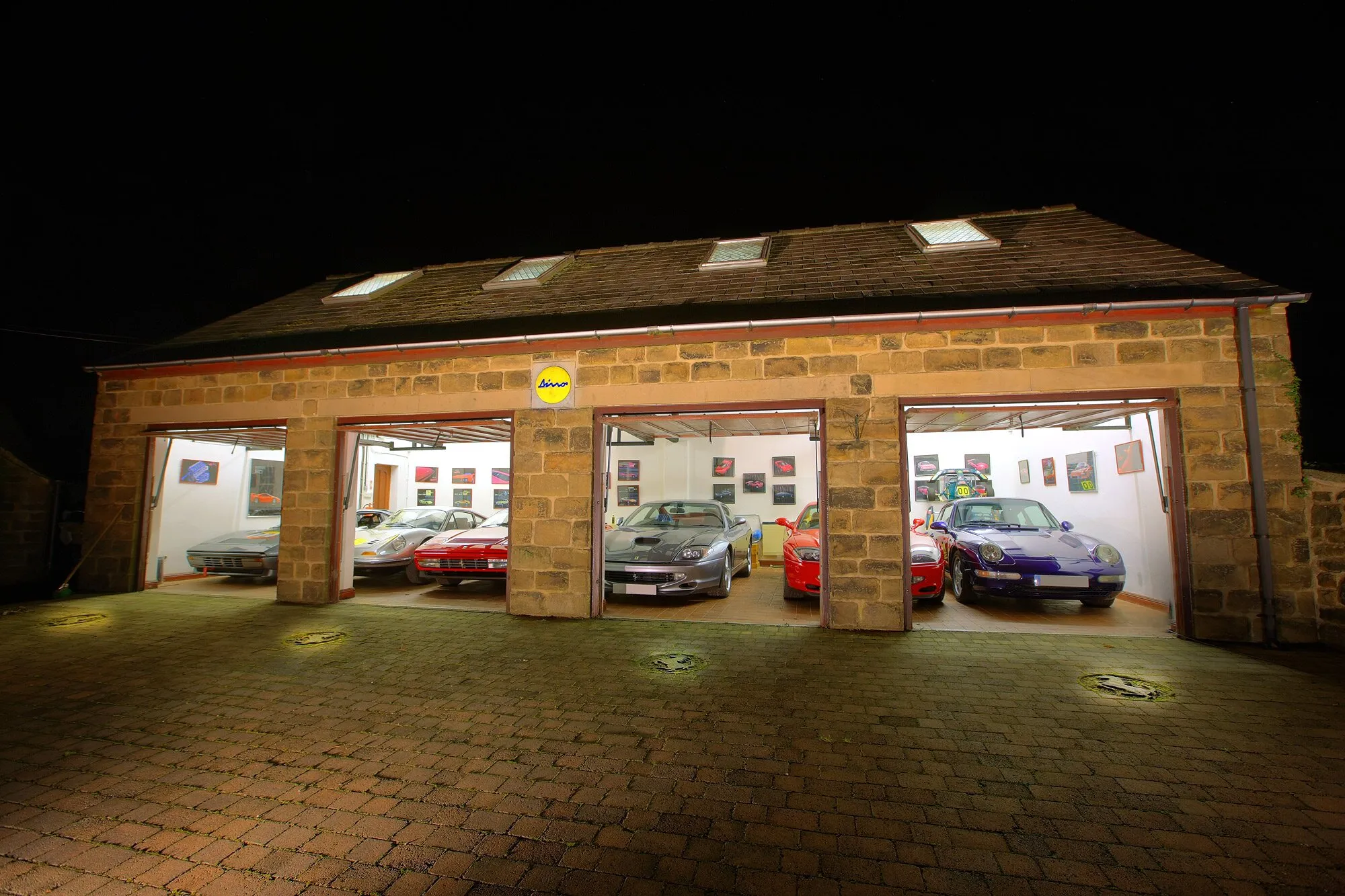 The stone barns at night, all four doors open and the cars lit inside