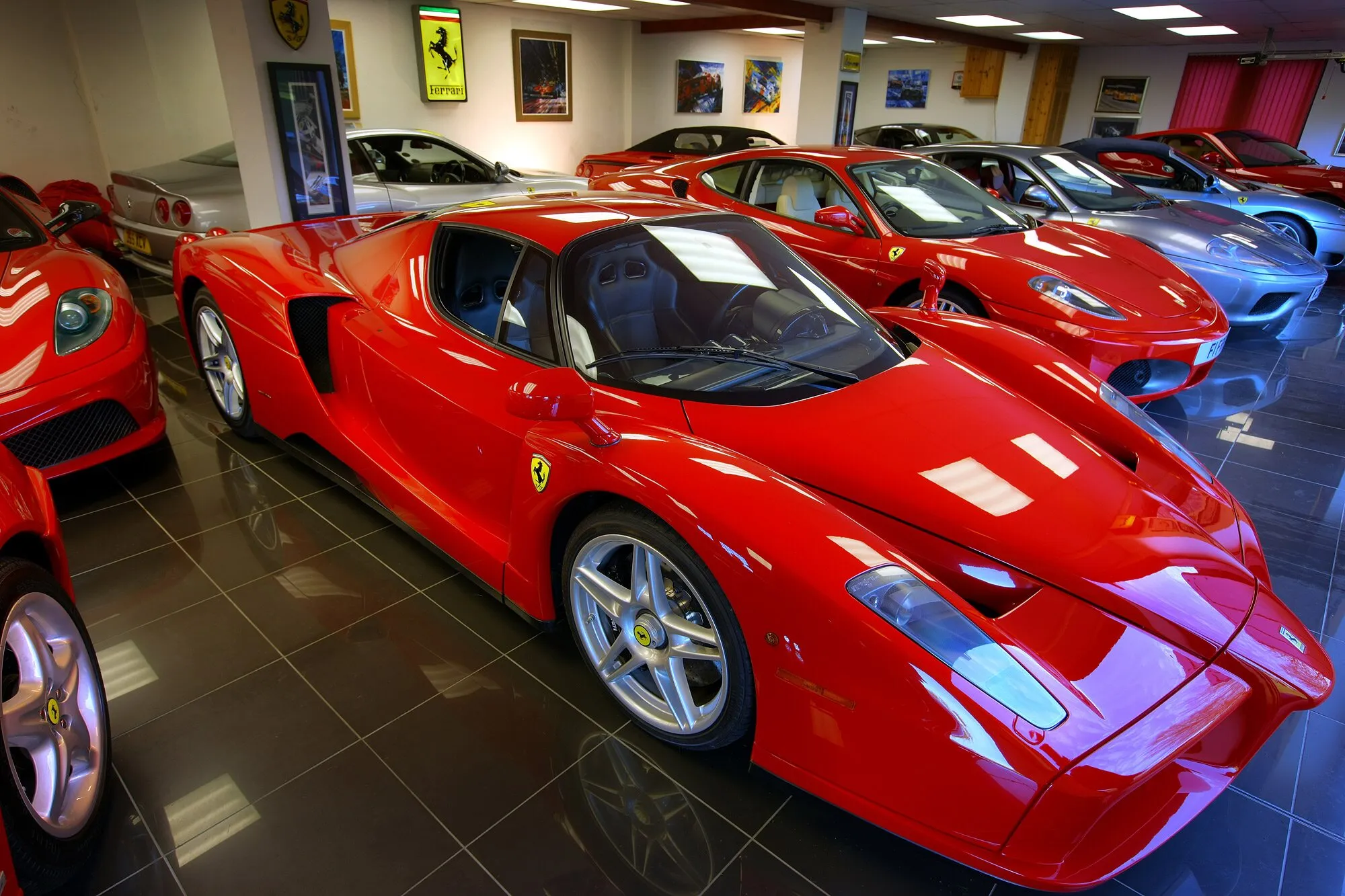 A red Ferrari Enzo in the showroom, with more Ferraris and framed prints behind