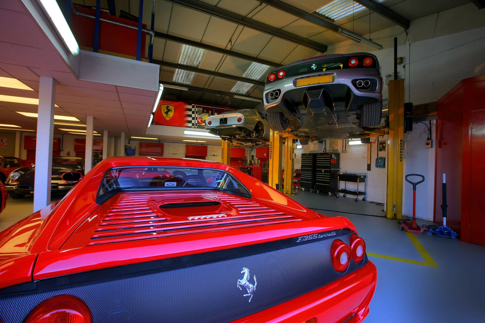 The workshop, with a red Ferrari 355 in the foreground and another car raised on a lift