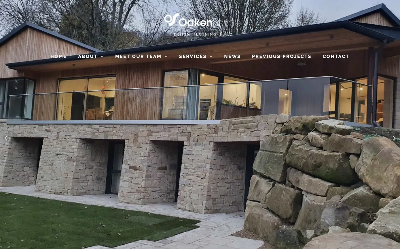 OakenStone homepage: a timber-clad house on a dry-stone base, built by the firm