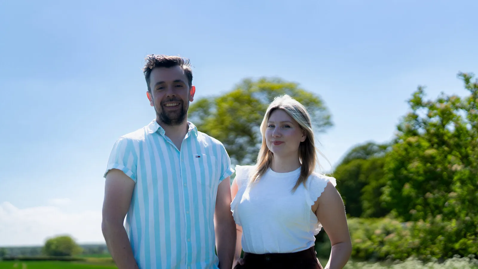 Will Charlton and Lizzie McLaughlin side by side in a field on a sunny day