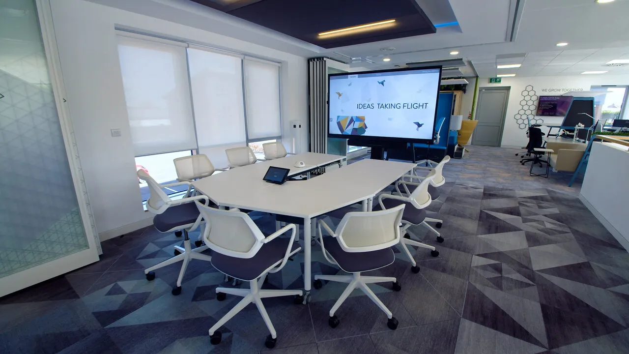 An empty conference room with a large screen at the end of the table