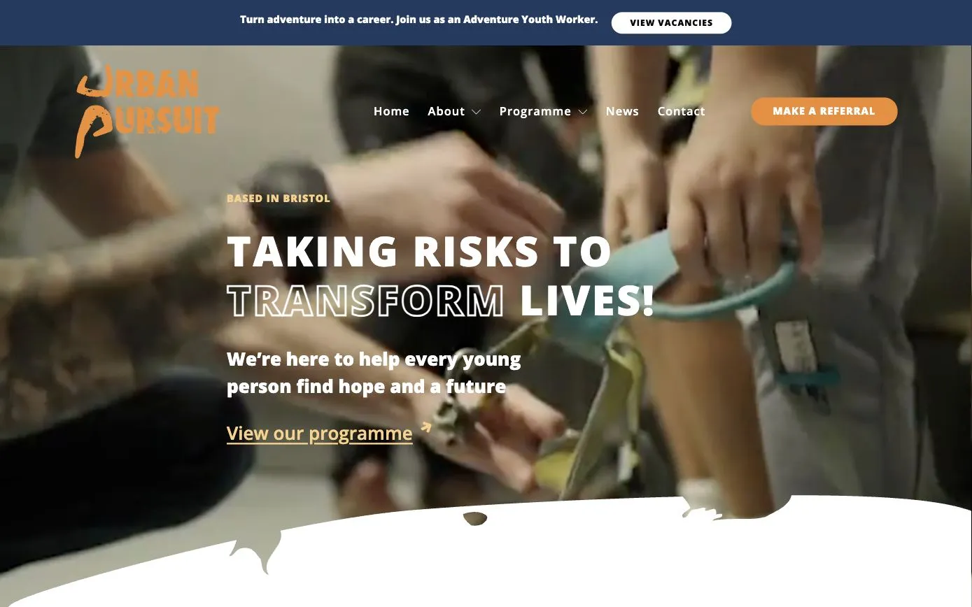 Urban Pursuit homepage: “Taking risks to transform lives!” over film of a climbing harness being fitted