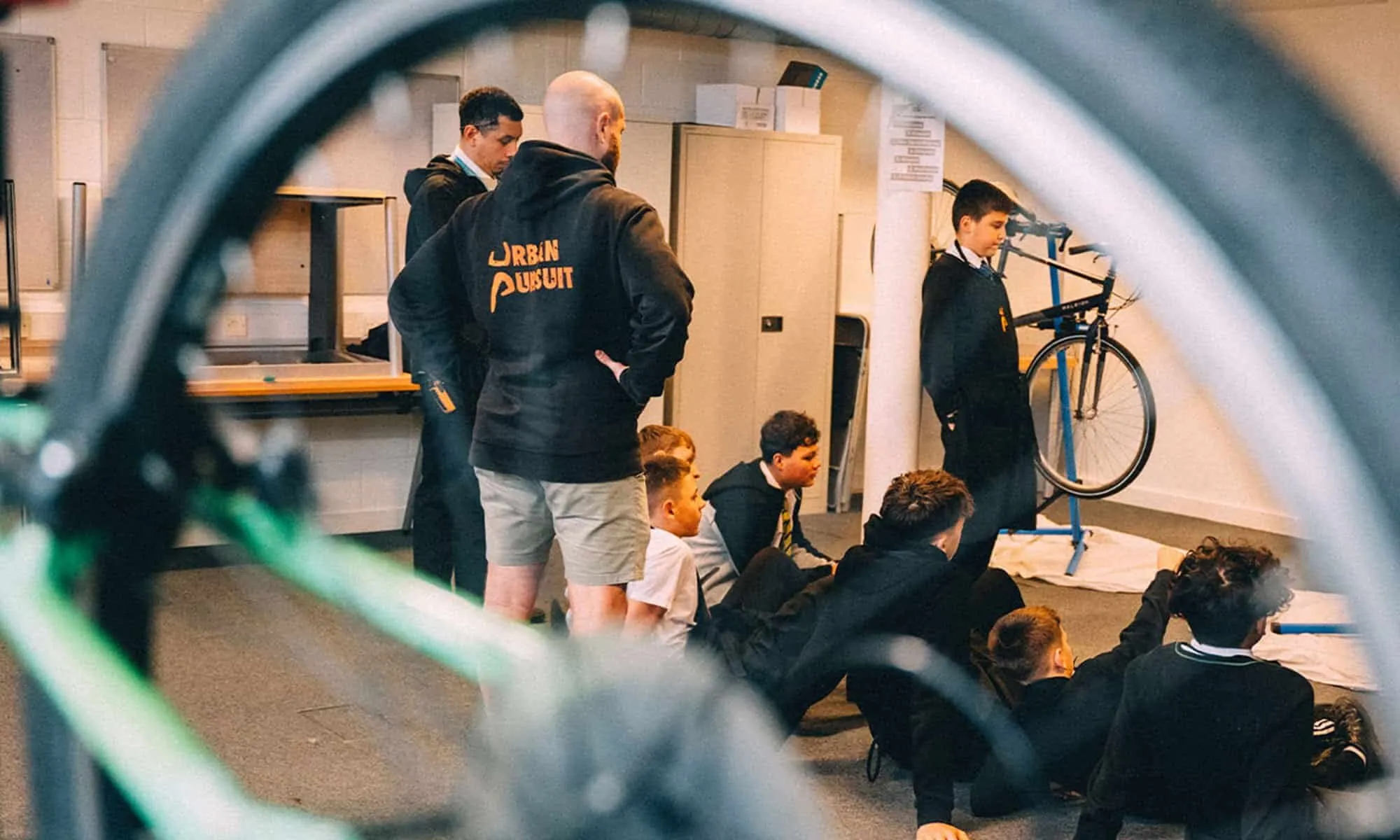 A bike repair session, seen through a bicycle wheel