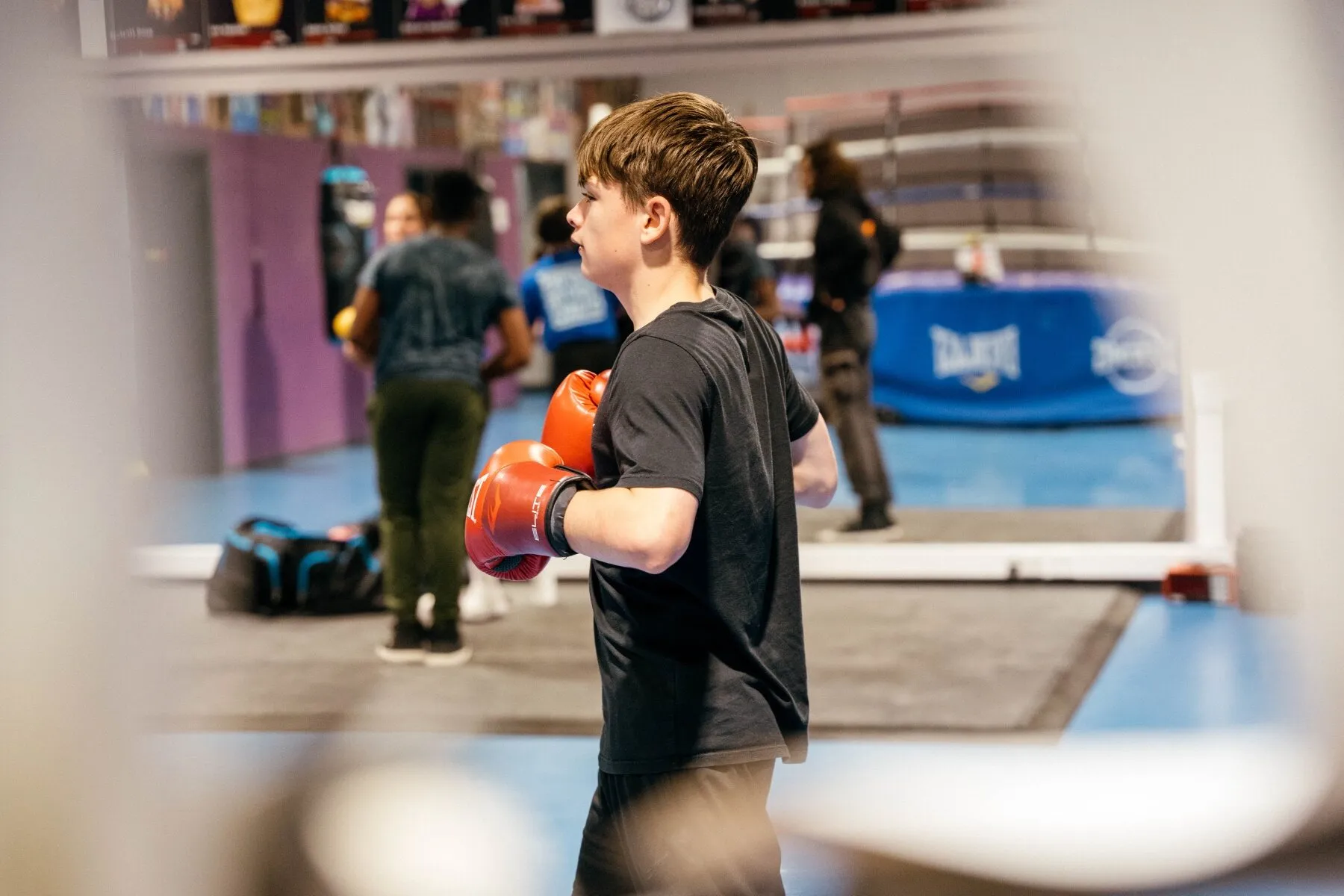 A young person in red boxing gloves training at a boxing gym