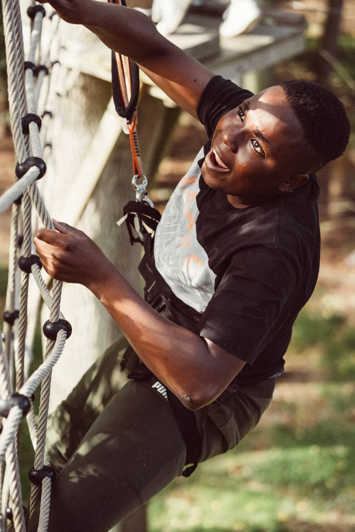 A young person climbing a rope ladder on a high ropes course
