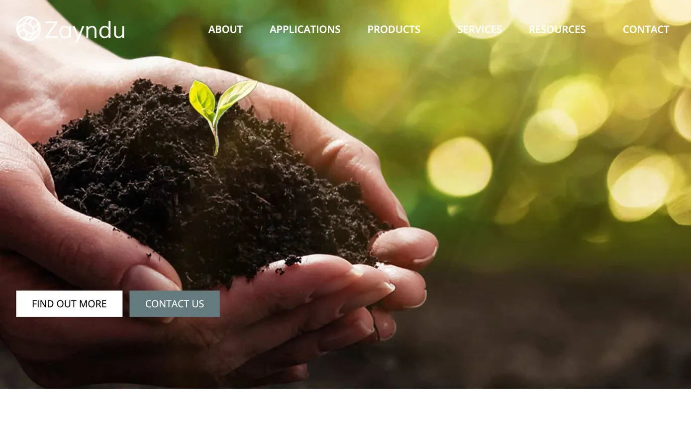 The 2022 site: Zayndu’s logo and menu over a photograph of cupped hands holding soil and a seedling, with Find out more and Contact us buttons