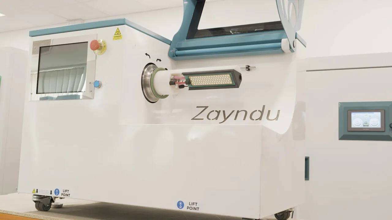 A white Zayndu machine in the lab, with its name on the side and a teal frame across the top